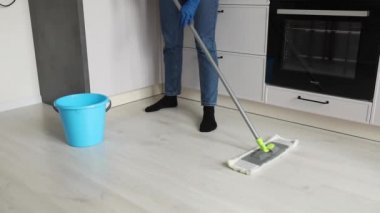 Bir adam mutfakta yerleri yıkıyor.