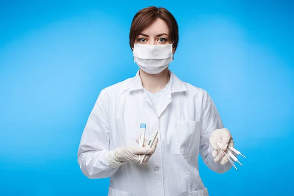 Красива біла жінка зі спеціальною медичною маскою робить експеримент з термометрами, портрет ізольований на білому тлі — стокове фото