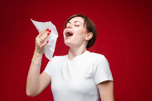 Frau niest in Gewebe. Isoliert auf Rot. — Stockfoto