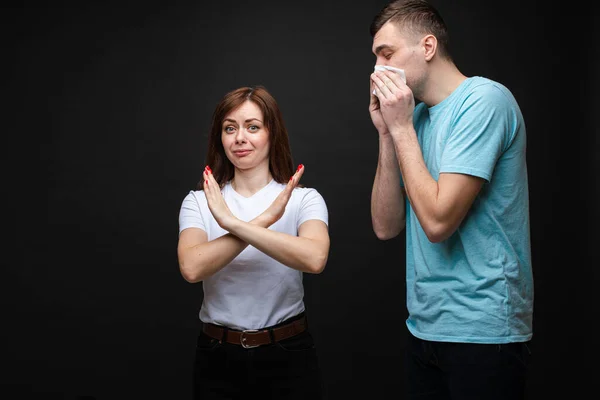 Young woman with stop gesture and a sneezing man.