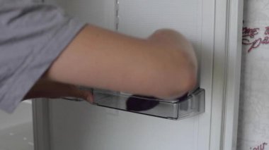 Kadın evdeki buzdolabını yıkıyor.
