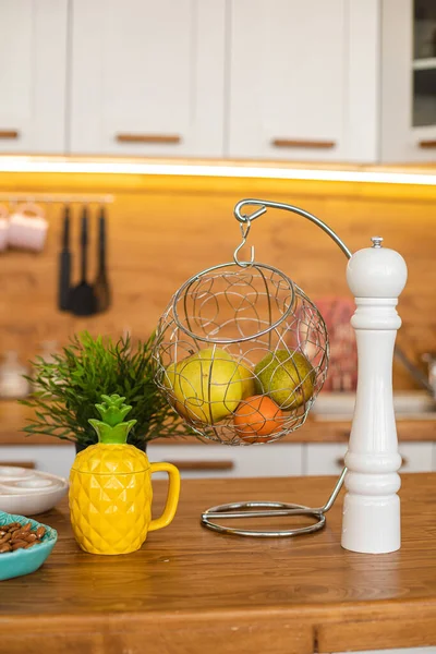 Maçã verde, pêra e tangerina laranja estão em um vaso de metal pendurado na cozinha — Fotografia de Stock