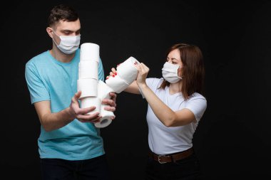 Beyaz maskeli bir çift koronavirüsten korkar ve tuvalet kağıdı için kavga ederler. Sarı arka planda izole edilmiş bir resim.