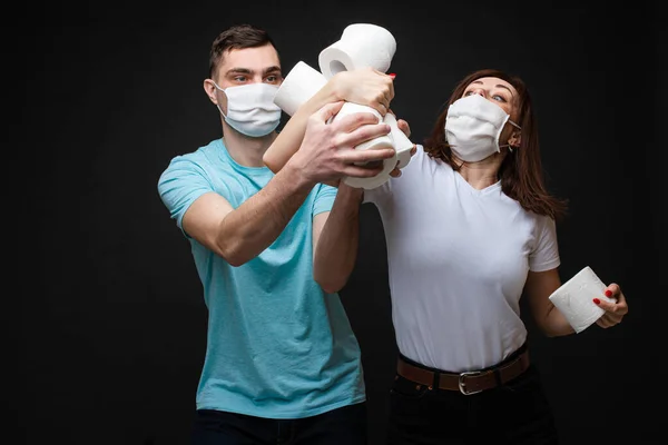 Verliefde paren in witte medische maskers zijn bang voor coronavirus en gevechten voor wc-papier, beeld geïsoleerd op gele achtergrond — Stockfoto