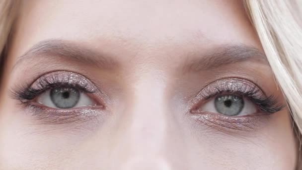 Kvinna med vackra stora blå ögon, långa svarta ögonfransar, glitter ögonskugga på dem — Stockvideo