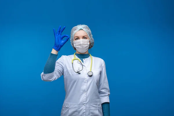 Красива жінка в білому медичному одязі, маска і фонендоскоп на плечах, картина ізольована на сірому фоні — стокове фото