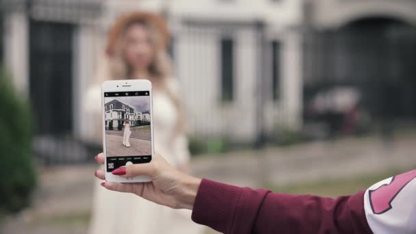 手持智能手机的手臂，为一位身着婚纱的女士拍照. — 图库视频影像