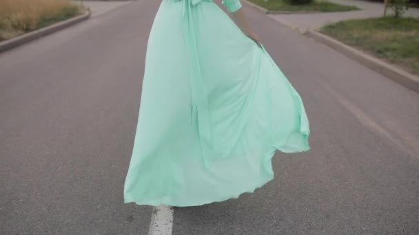 Hermosa mujer en vestido largo de menta y con sombrero blanco va a dar un paseo fuera — Vídeos de Stock