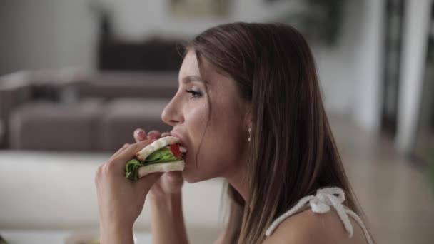 Beautiful lady enjoying sandwich during lunch in room — Stock Video