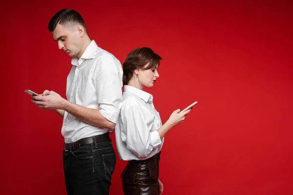 Couple d'amoureux serf internet et se tient l'un à l'autre, image isolée sur fond rouge — Photo