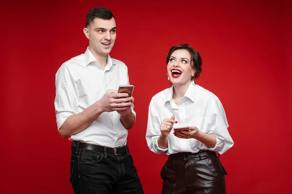 Jovem casal feliz com gadgets de pé em estúdio — Fotografia de Stock