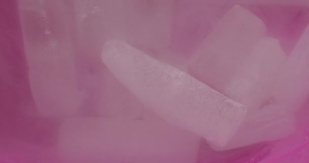 Muchos trozos de hielo seco se encuentran en un plato rosado y están llenos de agua — Vídeo de stock