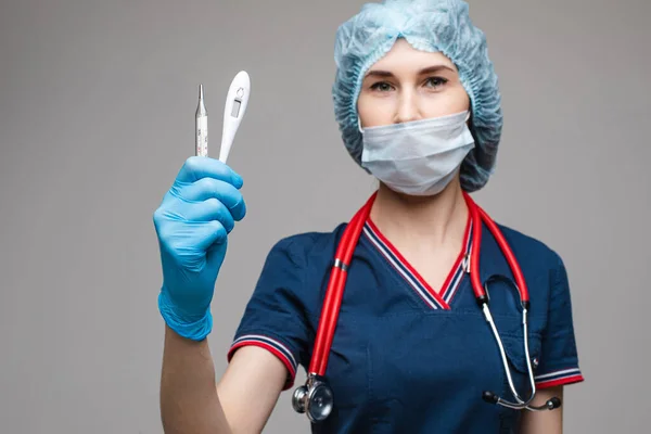 Портрет лікаря-жінки в медичному одязі з фонендоскопом навколо шиї тримає термометри, зображення ізольоване на білому тлі — стокове фото