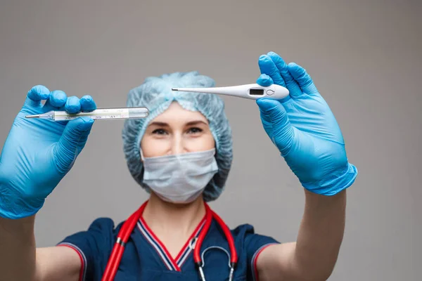 Портрет лікаря-жінки в медичному одязі з фонендоскопом навколо шиї тримає термометри, зображення ізольоване на білому тлі — стокове фото