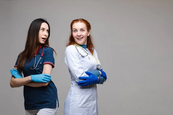 Портрет двух женщин-врачей в медицинской одежде с фонендоскопом на шее, на белом фоне — стоковое фото