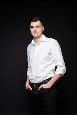 Ofis takım elbiseli güzel bir adamın portresi ellerini ceplerinde tutar, resim siyah arka planda izole olur.