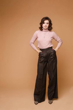 Stüdyoda poz veren şık bir kadın. Elleri ceplerinde poz veriyorlar..