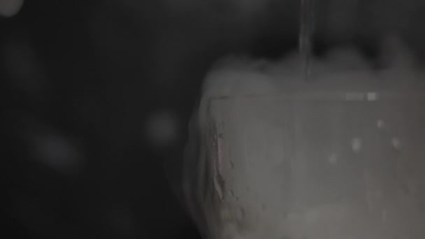 Pouring water into glass with dry ice. — Stock Video