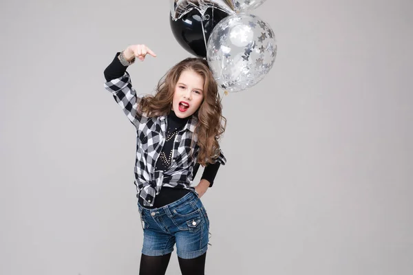 Cooles Pre-Teen Mädchen mit Rock-Zeichen. Sie zeigt Rock n Roll oder Hupzeichen, gestikuliert in die Kamera und schmückt ihre Lippen mit zwei Luftballons. Stock Studio Portrait isoliert auf grau. — Stockfoto
