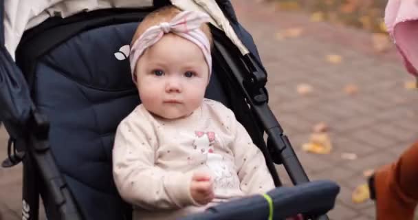 Relaks cute baby girl w łuku opaski w wózku dla dzieci. — Wideo stockowe