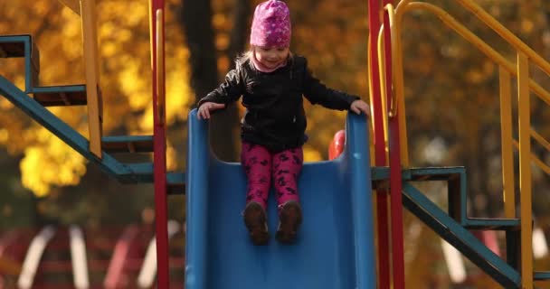 Linda niña con chaqueta negra sonríe y se regocija en el parque de otoño — Vídeo de stock