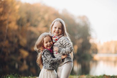 İki güzel kız kardeş ayağa kalkar ve birbirlerine sarılırlar.