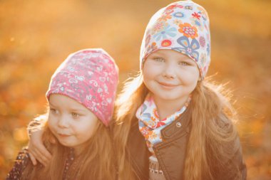 İki güzel kız kardeş ayağa kalkar ve birbirlerine sarılırlar.