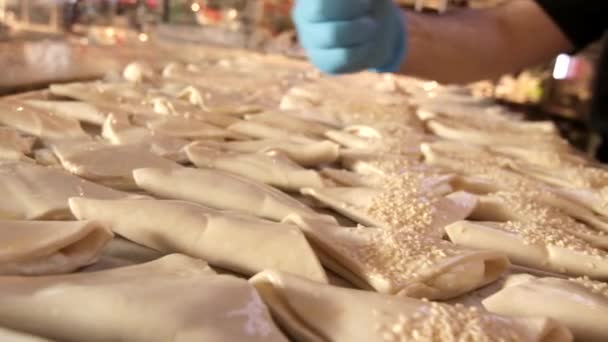 Scattering of sesame on fresh pastries — Stock Video