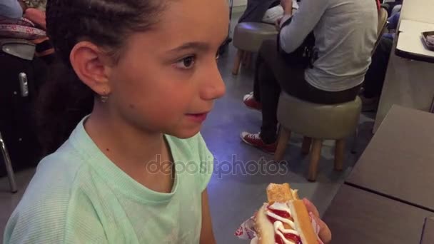 Niño comiendo perrito caliente en patio de comida — Vídeos de Stock