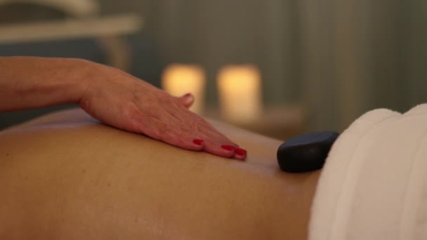 Гарячі камені на спині під час масажу — стокове відео