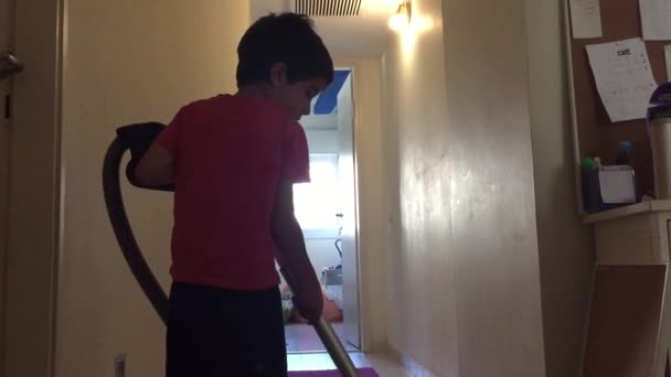 Ребенок использует очиститель вакуума, чтобы пыль ковер — стоковое видео