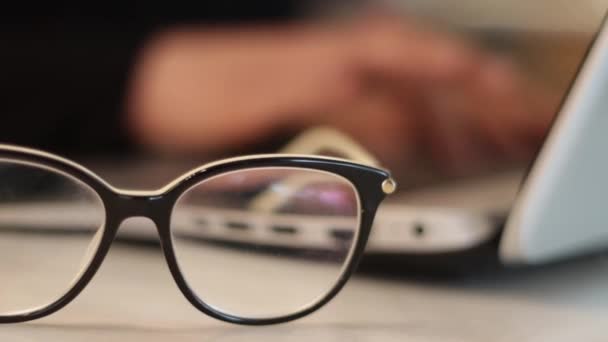 Woman with laptop picking up glasses — Stock Video