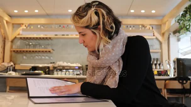 Mujer buscar opciones en el menú en un restaurante — Vídeo de stock