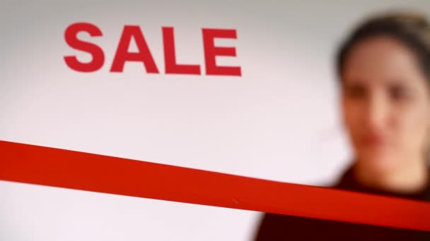 Shot of Woman cutting red ribbon with sale sign — Stock Video