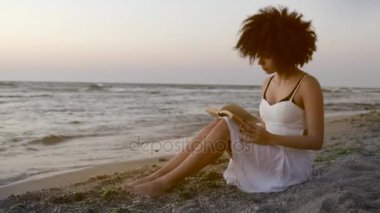 Sahil kitap ile oturan ilham kadın