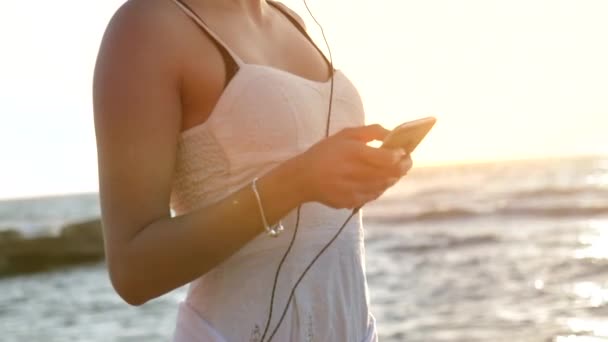 Schot van jonge vrouwelijke smartphone te houden op het strand — Stockvideo