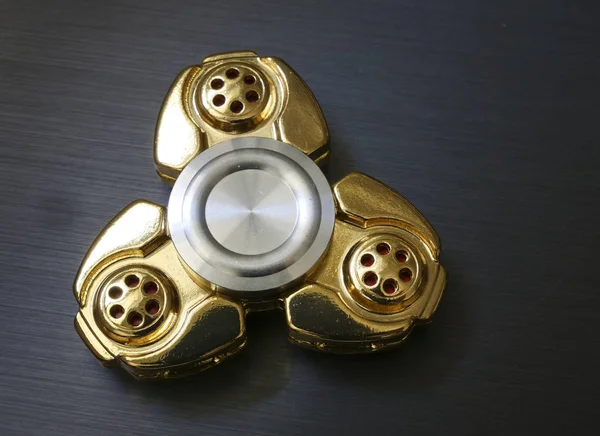 Altın topluca spinner oyuncak karanlık aurface üzerinde — Stok fotoğraf
