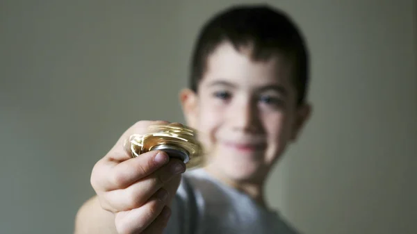 Niño sosteniendo fidget spinner juguete dorado — Foto de Stock