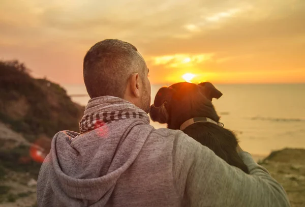 Homem e seu cão fiel desfrutando de um pôr do sol oceano — Fotografia de Stock