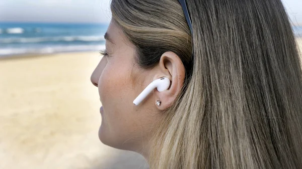 Jovem mulher ouvir música usando fones de ouvido sem fio bluetooth — Fotografia de Stock