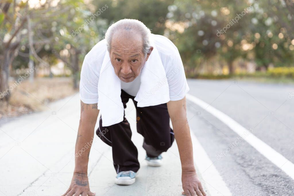 Front view Asian elderly exercise. Senior man in position ready to run. Determined man ready for a sprint. health lifestyle and Exercise Start Up Concept