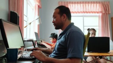Evden çalışıyorum. Asyalı anne ve baba oğlumla yatak odasında bilgisayar kullanıyorlar. Sabahleyin pencereden gönderilen güneş ışığı..