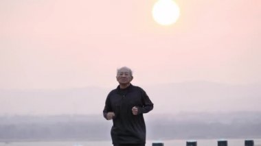 Asyalı yaşlılar egzersizi. Son sınıf öğrencisi sabah güneş doğarken yolda koşuyor. sağlık yaşam tarzı ve egzersiz kavramı