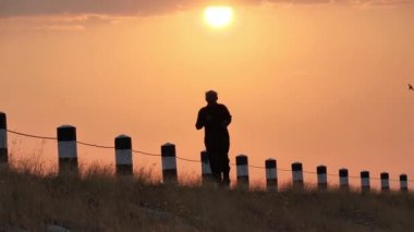 Asyalı yaşlılar için ön görüş egzersizi. Son sınıf öğrencisi sabahın köründe Slow Motion 'ın arkasında gündoğumuyla yolda koşuyor. sağlık yaşam tarzı ve egzersiz kavramı