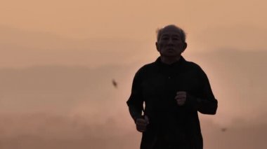 Asyalı yaşlılar için ön görüş egzersizi. Son sınıf öğrencisi sabah Yavaş Hareket 'in arkasında gündoğumuyla yolda yürüyor. sağlık yaşam tarzı ve egzersiz kavramı