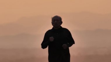 Asyalı yaşlılar için ön görüş egzersizi. Son sınıf öğrencisi sabah Yavaş Hareket 'in arkasında gündoğumuyla yolda yürüyor. sağlık yaşam tarzı ve egzersiz kavramı