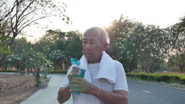 夕方に太陽の光がある公園で運動した後 アジアの高齢者飲料水を閉じます 健康ライフスタイルと運動の概念 スローモーション — ストック動画