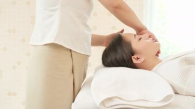 Genç Asyalı kadın güzellik salonunda masaj yaptırıyor. Yüz masajı, rahatlatıcı masaj, kaplıca ve vücut bakımı. Dolly kaydırıcı