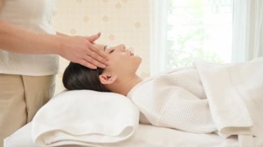 Genç Asyalı kadın güzellik salonunda masaj yaptırıyor. Yüz masajı, rahatlatıcı masaj, kaplıca ve vücut bakımı. Yavaş Hareket