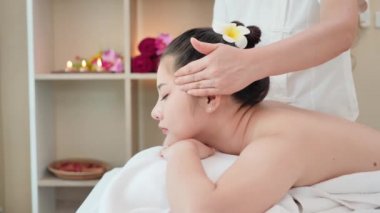 Genç Asyalı kadın güzellik salonunda kaplıca masajı yaptırıyor. Yüz masajı, rahatlatıcı masaj, kaplıca ve vücut bakımı. Yavaş Hareket